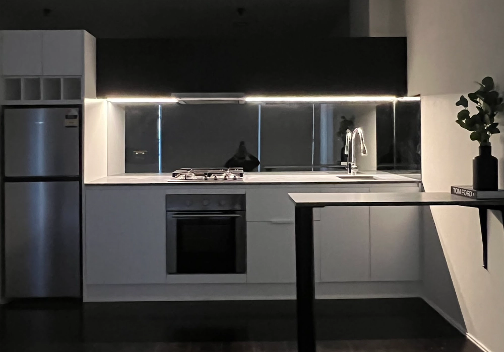 modern two tone studio apartment kitchen with 20mm stone bench top and mirror splash back