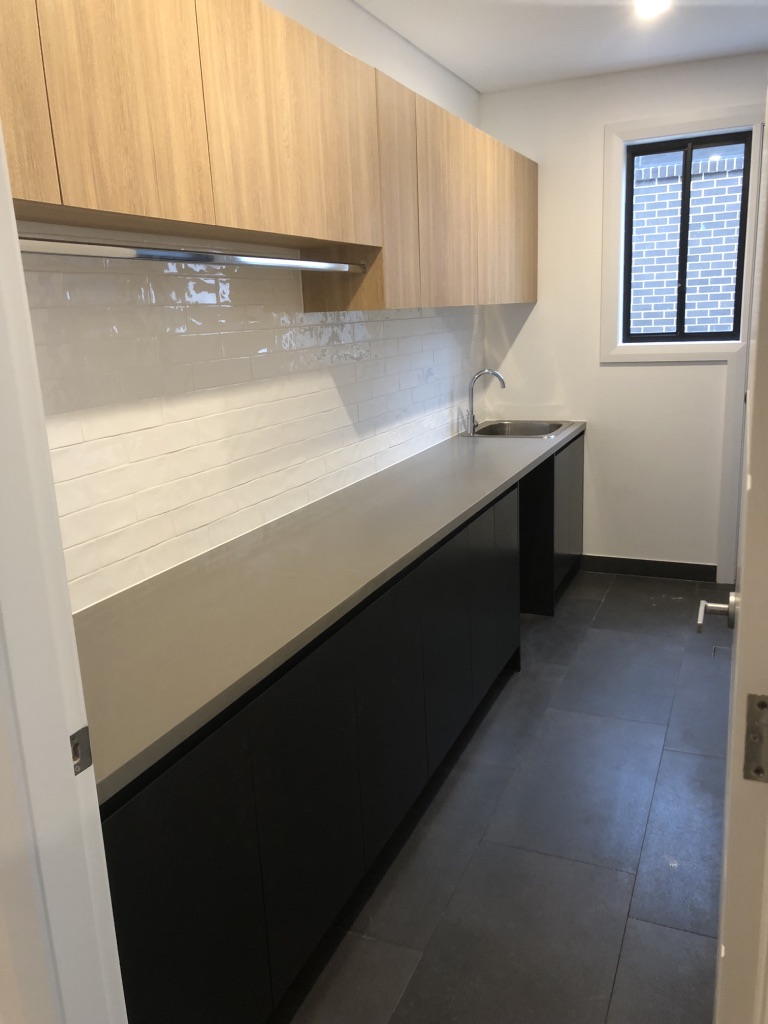 two tone laundry, laundry renovation, black laundry cabinet, timber laundry cabinet, laundry hanging, hanging rail, tile splash back, laundry splash back, white splash back, white tile splash back, dark grey floor tiles, charcoal floor tiles, laundry sink, chrome tap ware, silver tap ware